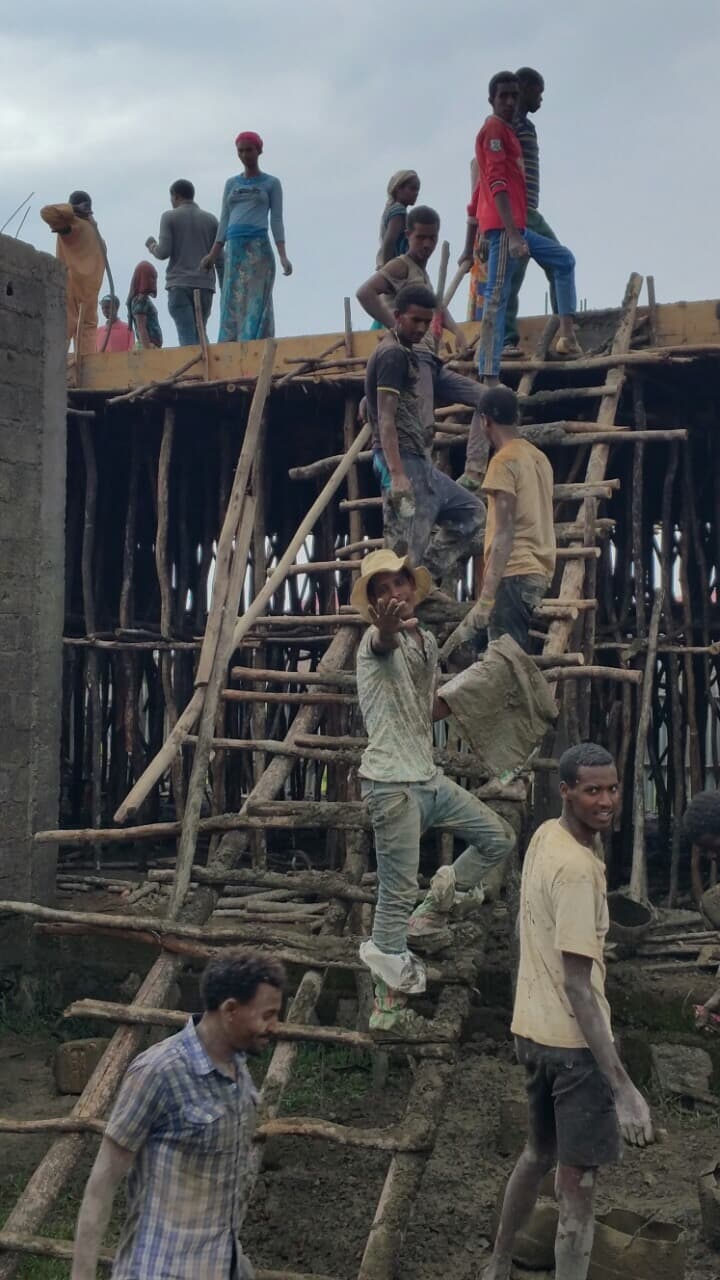 A large construction team working together on timber scaffolding and concrete formwork