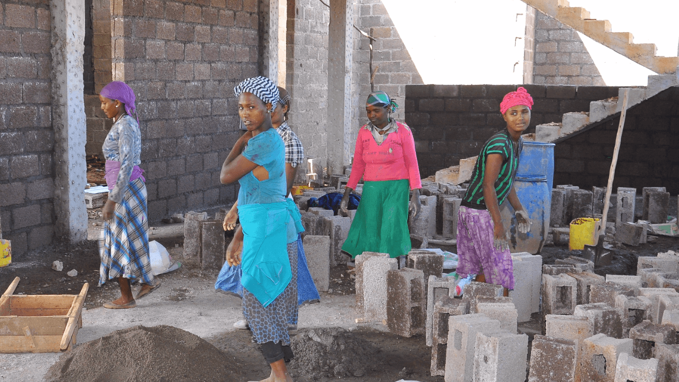 Women working among newly made concrete blocks inside the hospital structure
