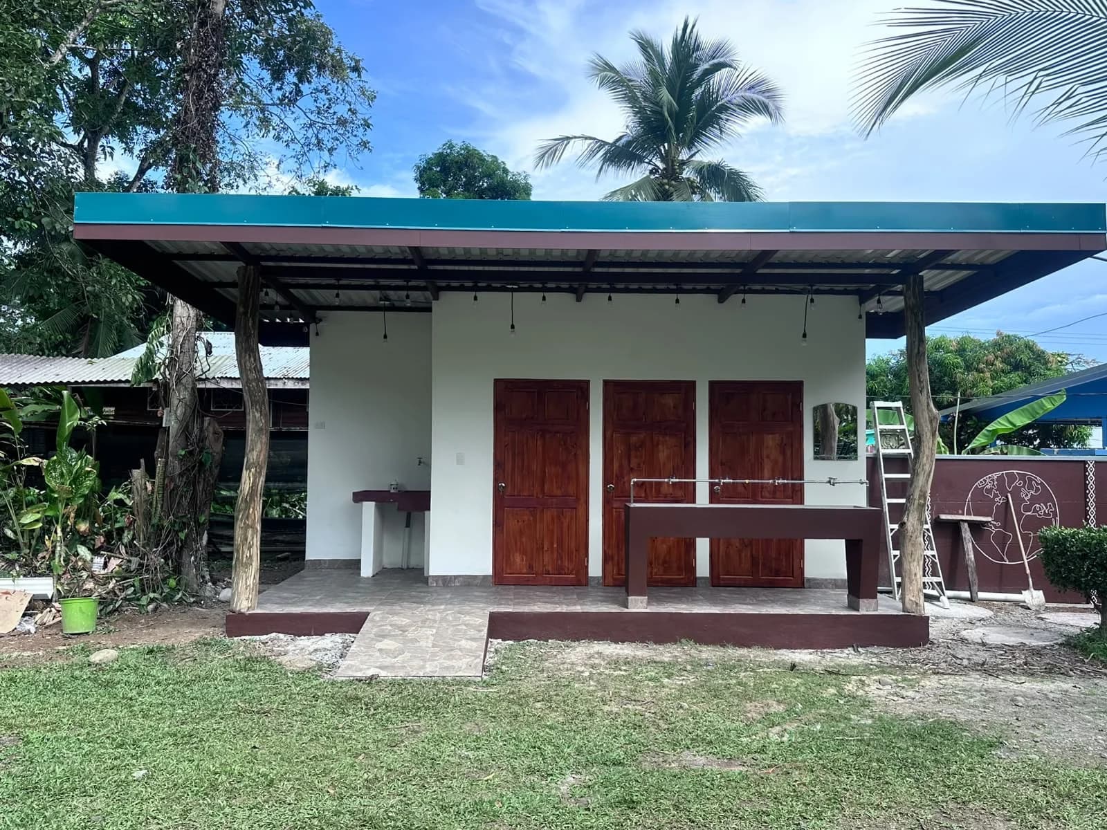 El Puente building with timber posts, three wooden doors, and outdoor sinks in Costa Rica